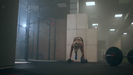A-woman-performs-push-UPS-with-dumbbells.-burpee-with-weight.-The-jerk-of-the-dumbbells-over-your-head.-A-woman-trains-with-a-heavy-weight.